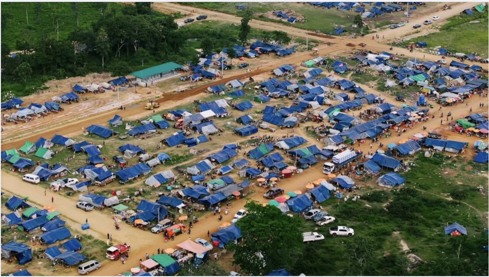 Aerial view of the displaced-families camp — rows of tarpaulin shelters along dirt roads