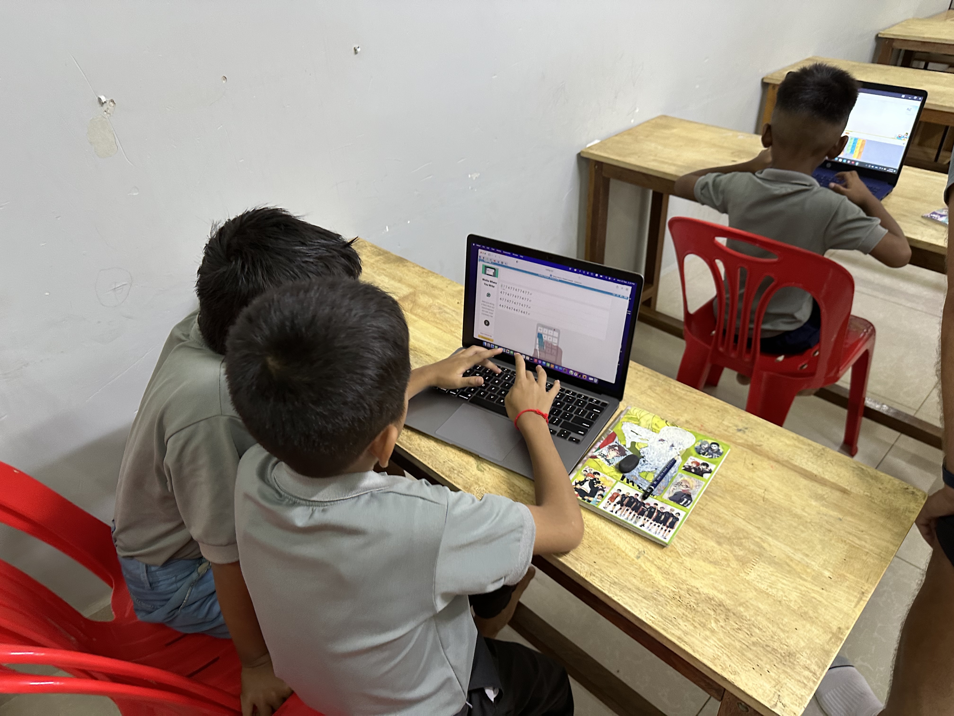 Boys learning to type on laptops in a classroom in Poipet